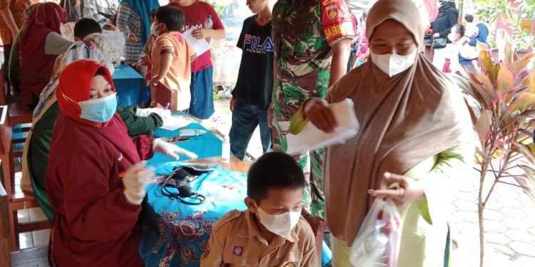 Dengan Penuh Kehangatan Babinsa Dampingi Anak-anak Terima Vaksin